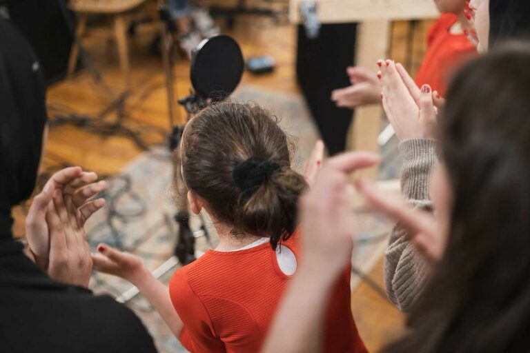 A group of people in a recording studio, singing and clapping hands