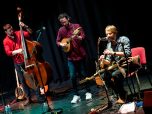 Three musicians performing on stage with instruments