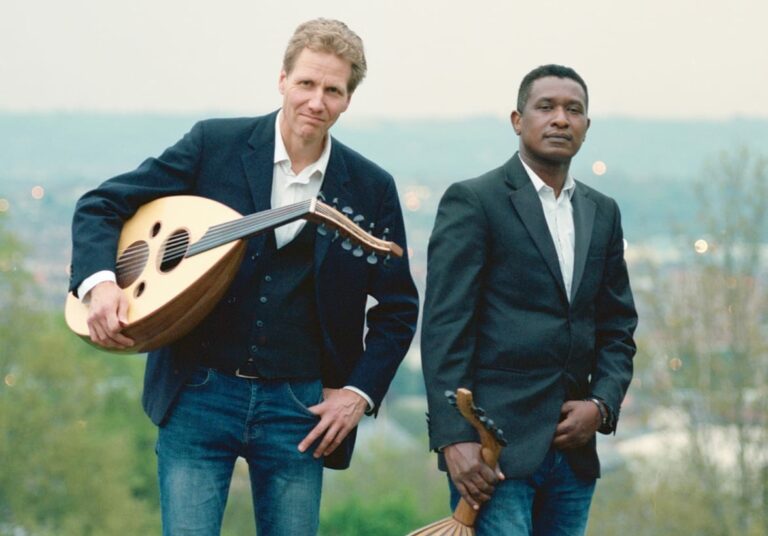 Two musicians holding large string instruments outdoors