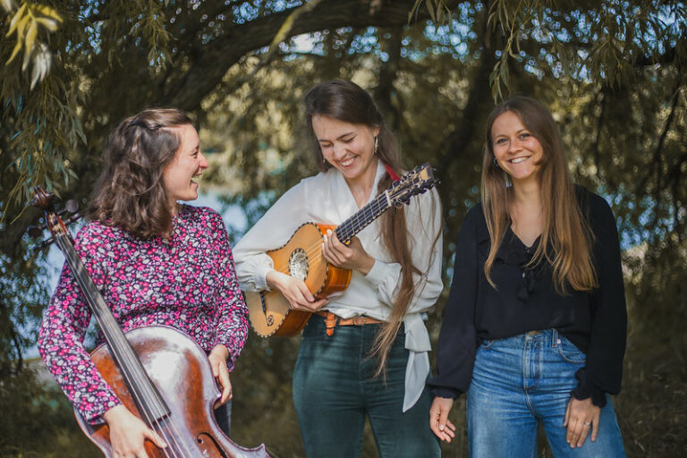 Three musicians holding string instruments outdoors