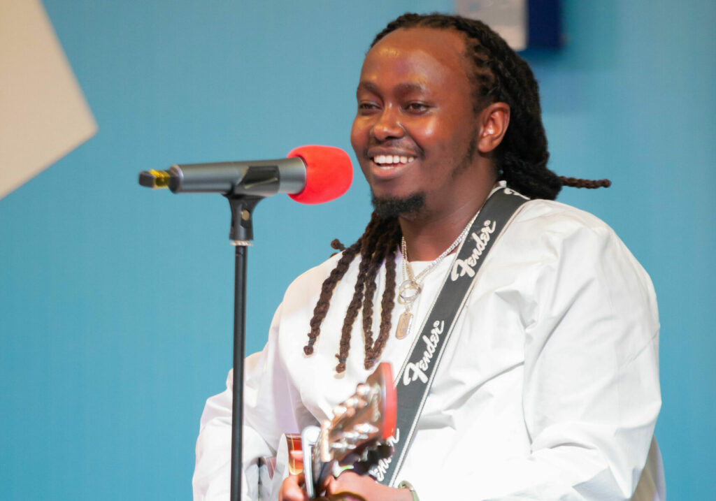 A musician playing guitar and singing into a microphone on stage
